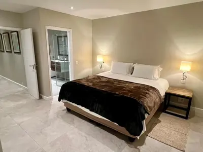 a bedroom with a large bed with two lamps at Dolphin Beach Cabana in Table View