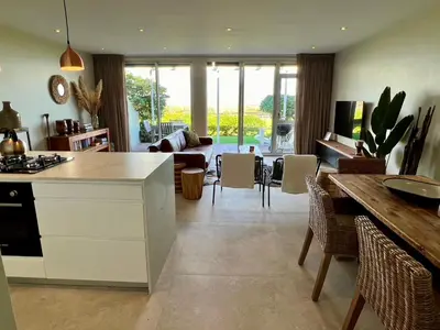 a kitchen and living room with a table and chairs at Dolphin Beach Cabana in Table View