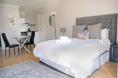 a bedroom with a large white bed and a table at Pringle Nest in Cape Town
