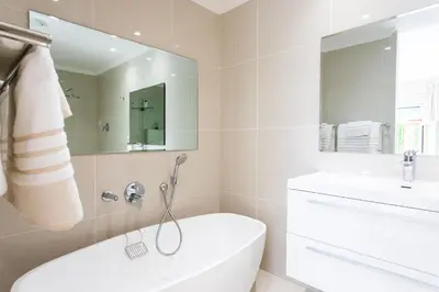 a white bathroom with a tub and a sink at Koetsiershuis in Stellenbosch