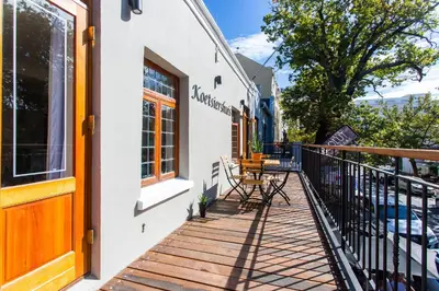 a balcony of a building with a table and chairs at Koetsiershuis in Stellenbosch