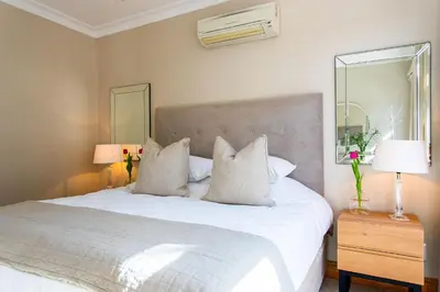 a bedroom with a large white bed with pillows at Koetsiershuis in Stellenbosch