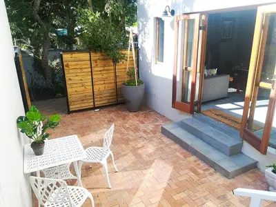 a patio with a table and chairs next to a door at Culemborg Cottage in Cape Town