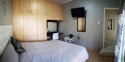 a bedroom with a white bed and wooden cabinets at TwinnPalms Accommodation in Cape Town