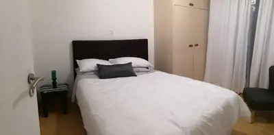 a bedroom with a bed with white sheets and pillows at TwinnPalms Accommodation in Cape Town