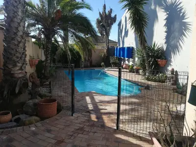 a swimming pool in a backyard with palm trees at TwinnPalms Accommodation in Cape Town