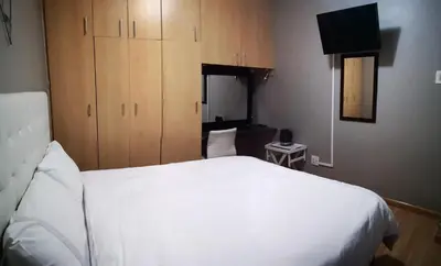 a bedroom with a white bed and wooden cabinets at TwinnPalms Accommodation in Cape Town
