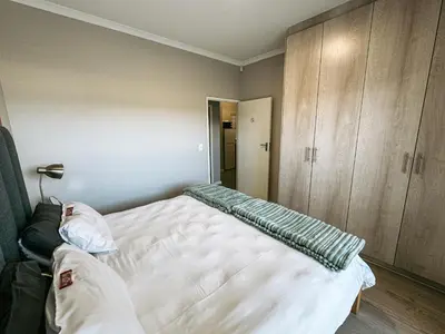 a bedroom with a bed and wooden cabinets at Nemesia Court in Durbanville