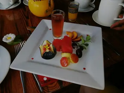 a white plate with fruit and a drink on a table at Rouxwil Country House in Caledon