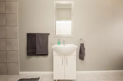 a white bathroom with a sink and a mirror at Villa Eike in Grabouw