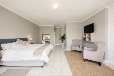 a bedroom with a bed and a tv and a chair at Villa Eike in Grabouw