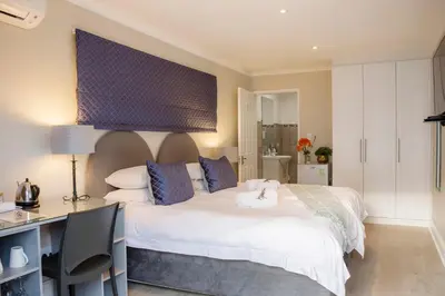 a bedroom with a white bed with a desk and a desk at Maroela House Guest Accommodation in Bellville