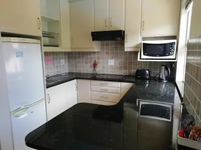 a kitchen with white cabinets and a black counter top at Maroela House Guest Accommodation in Bellville