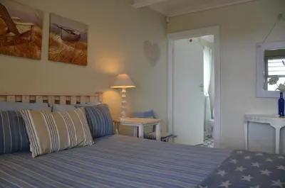 a bedroom with a bed and a table with a lamp at Beach Cottage 1 in Hermanus