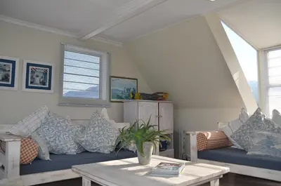 a living room with a blue couch and a table at Beach Cottage 1 in Hermanus