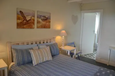 a bedroom with a bed and two paintings on the wall at Beach Cottage 1 in Hermanus