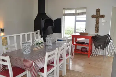 a kitchen with a table with chairs and a cross on the wall at Beach Cottage 2 in Hermanus