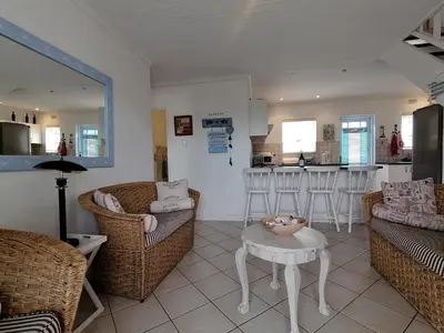 a living room with chairs and a table and a kitchen at Beach Cottage 2 in Hermanus