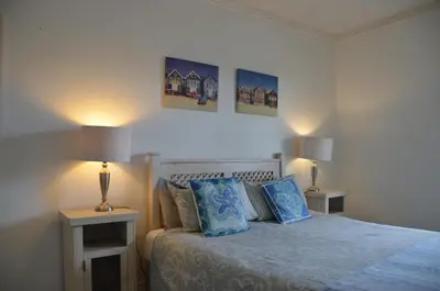 a bedroom with a bed with blue pillows and two lamps at Beach Cottage 2 in Hermanus