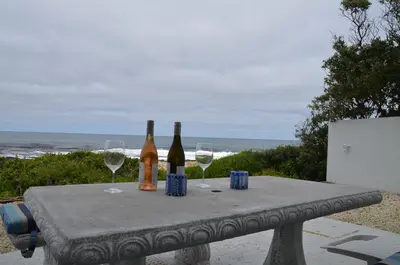 a table with two bottles and two glasses of wine at Beach Villa Apartment in Hermanus