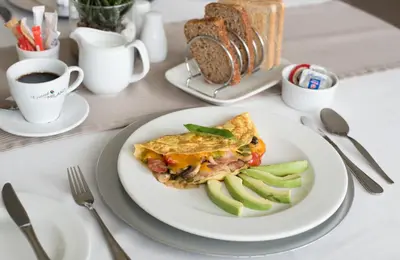 a plate of food with a omelet and pickles on a table at Bell Rosen Guest House in Bellville