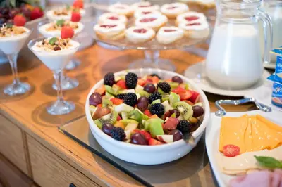 a table with a bowl of fruit salad and other desserts at Bell Rosen Guest House in Bellville