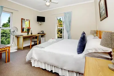 a bedroom with a large white bed and a desk at Bell Rosen Guest House in Bellville