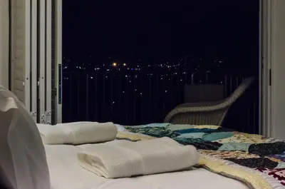 two white towels sitting on a bed on a balcony at Somerset View Guest House in Somerset West