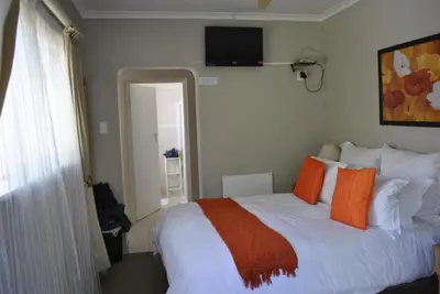 a bedroom with a large white bed with orange pillows at Cotswold House Residence in Cape Town