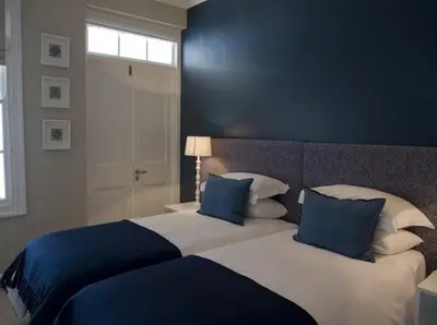 a bedroom with two beds with blue and white pillows at Kenjockity Self Catering Apartments in Hermanus