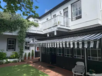a white building with a black and white awning at Sandown Lodge in Cape Town