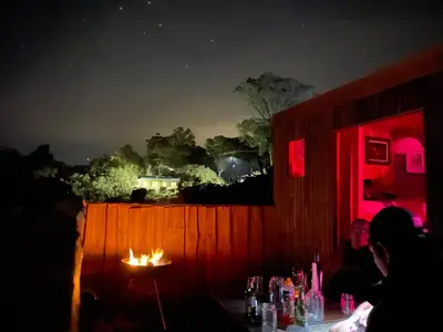 a group of people sitting around a table with a fire at McBains in Breerivier