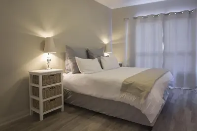 a bedroom with a bed and a night stand with a lamp at 2 Bedroom apartment with Breathtaking Views! in Cape Town