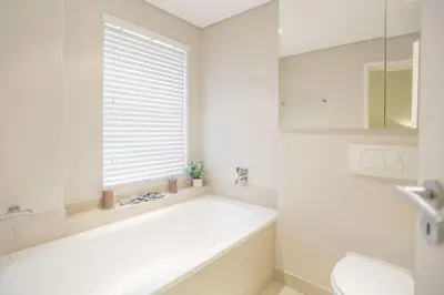 a white bathroom with a tub and a window at 2 Bedroom apartment with Breathtaking Views! in Cape Town
