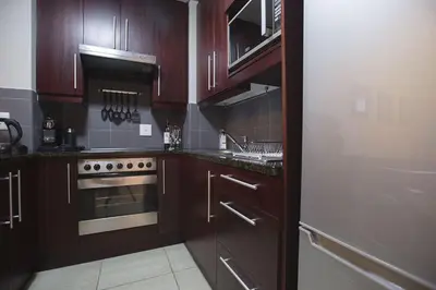 a kitchen with wooden cabinets and a stove top oven at 2 Bedroom apartment with Breathtaking Views! in Cape Town