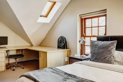 a bedroom with a bed and a desk with a computer at Le Arc Manor House in Franschhoek