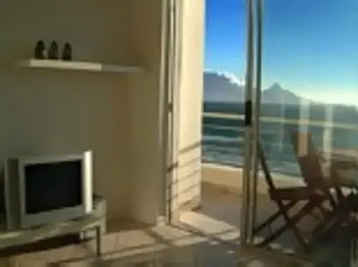 a living room with a television and a view of the ocean at WhiteSands in Cape Town