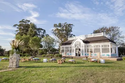 a building in a park with benches in the grass at Wild Clover Cottages in Stellenbosch