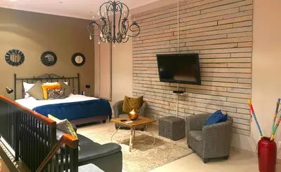 a bedroom with a bed and a tv on a wall at Franschhoek Studio in Franschhoek