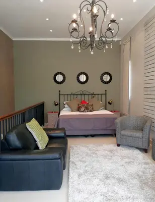 a bedroom with a bed and a couch and a chandelier at Franschhoek Studio in Franschhoek