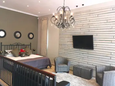 a bedroom with a bed and a tv on a wall at Franschhoek Studio in Franschhoek