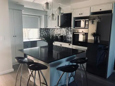 a kitchen with a black island with bar stools at 67 Whale Rock Estate, Hermanus in Hermanus
