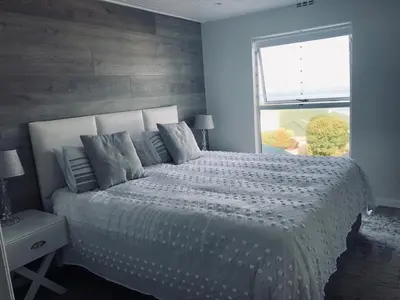 a bedroom with a large bed and a window at 67 Whale Rock Estate, Hermanus in Hermanus