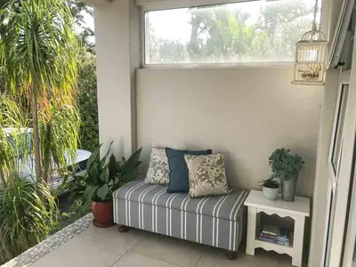 a bench on a porch with plants and a window at Protea Suite in Cape Town