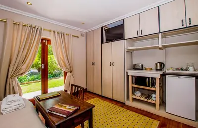 a living room with a table and a kitchen at Ladera - Vista Self-catering Guesthouse in Paarl