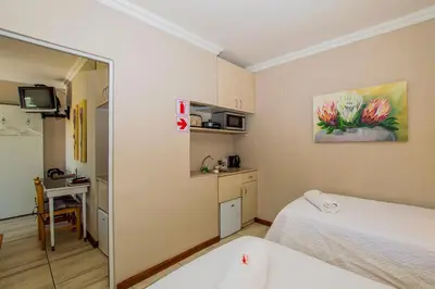 a room with two beds and a kitchen with a table at Ladera - Vista Self-catering Guesthouse in Paarl