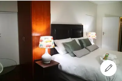a bedroom with a white bed and a lamp at The Room in Cape Town
