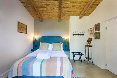 a bedroom with a bed with a blue head board at Bartinney Private Cellar Banhoek in Stellenbosch
