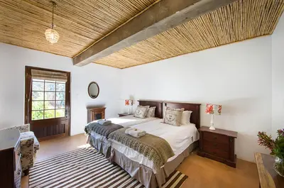 a bedroom with a large bed and a wooden ceiling at Bartinney Private Cellar Banhoek in Stellenbosch