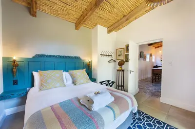 a bedroom with a bed with a teddy bear on it at Bartinney Private Cellar Banhoek in Stellenbosch
